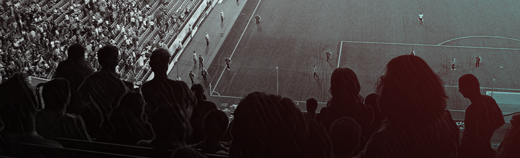 Black and white image of a view from a stadium seat looking down at a football pitch